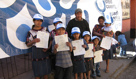 Dos adultos y siete niñas y niños colombianos muestran sus tarjetas de identificación emitidas durante una campaña de registro e identificación apoyada por PUICA en Quibdó, Chocó. 